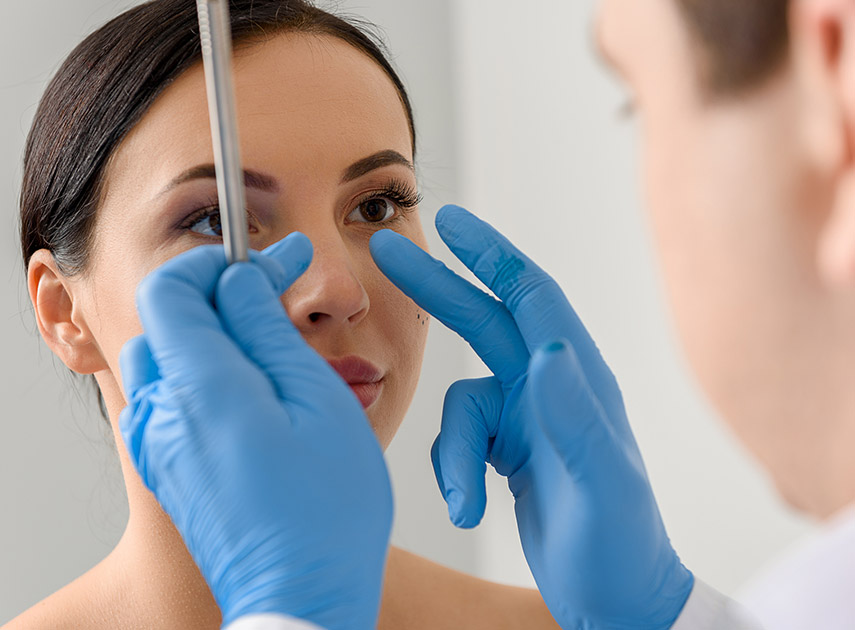 Doctor-examining-female-patient's-nose